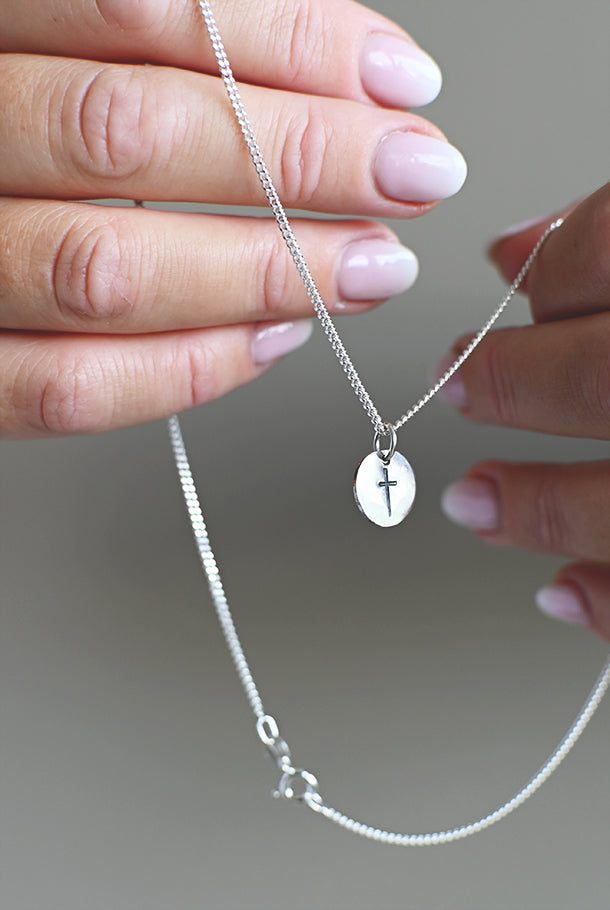 Handtillverkat silversmycke: Kors på rund platta